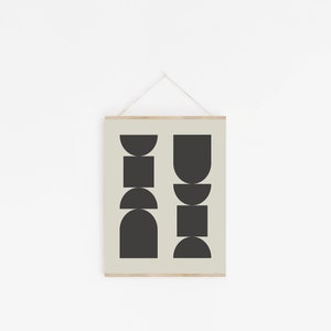 May include: A black and white geometric print with abstract shapes in a minimalist style. The print is framed and hanging on a white wall.