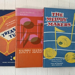 Puede incluir: Tres libros de música vintage con cubiertas coloridas. Los libros se titulan "Treasures", "Happy Harmonies" y "The Melody Makers". Las cubiertas presentan notas musicales e ilustraciones en naranja, rosa y azul. Los libros forman parte de la serie "Music Pathways".
