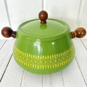 May include: Green enamel fondue pot with wooden handles and a yellow and green geometric pattern around the base.