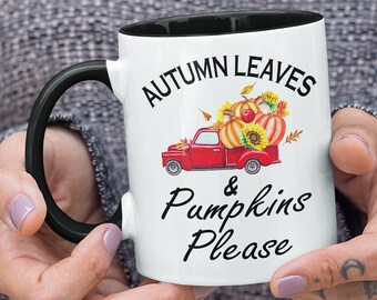 May include: A white ceramic mug with a black handle and interior rim. The mug features a graphic of a red pickup truck carrying pumpkins, sunflowers, and autumn leaves. The text "AUTUMN LEAVES & Pumpkins Please" is printed in black lettering.