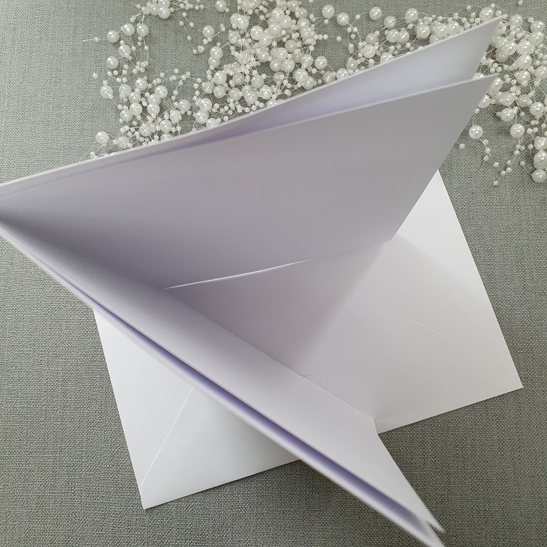 May include: A white card folded into a triangle shape. The card is blank and has a smooth surface.