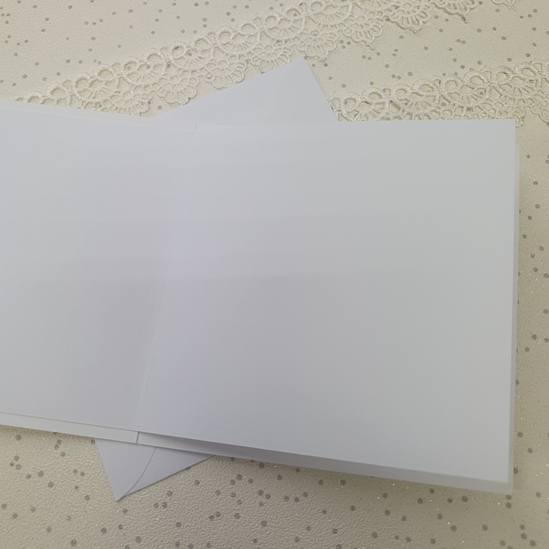 May include: Two blank white greeting cards stacked on top of each other. The cards are on a white background with a white lace pattern.
