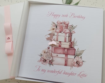 May include: A pink and white birthday card with a stack of presents decorated with pink flowers and rhinestones. The card reads "Happy 20th Birthday" and "To my wonderful daughter Lottie".
