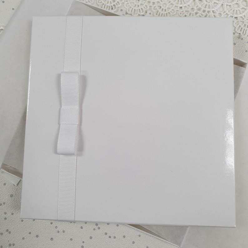 May include: A white card with a white satin ribbon and bow. The card is blank and ready for writing.