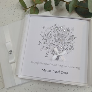 May include: A white card with a silver glitter tree design and the text "Happy Diamond Wedding Anniversary Mum and Dad". The card is in a white box.