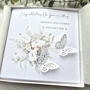 May include: A white card with a floral design and two white butterflies. The card says "Congratulations on your wedding" and "Amanda and Andrew 15th July 2025".