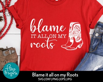 May include: Red t-shirt with white text that reads "blame it all on my roots" and a pair of white cowboy boots.