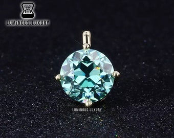 May include: A round, light blue gemstone pendant with a gold setting. The pendant is on a black background.