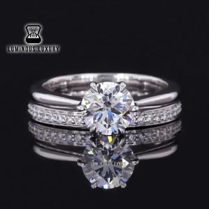 Peut inclure: Une bague de fiançailles en argent avec un grand diamant rond et clair au centre et une bande de diamants plus petits autour de la base.