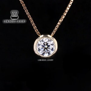 May include: A gold chain necklace with a round, bezel-set, clear gemstone pendant.