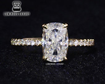 May include: A gold engagement ring with a large, clear, cushion-cut diamond center stone and a pave diamond band.