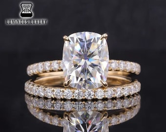 May include: A gold engagement ring set with a large, cushion-cut diamond center stone and a matching band with smaller diamonds.