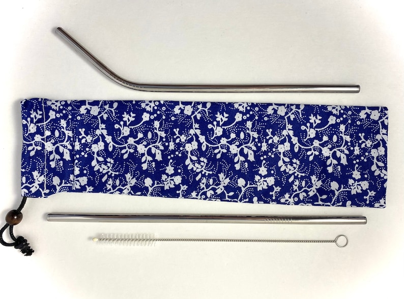 Pode incluir: Um conjunto de duas palhas de a&ccedil;o inoxid&aacute;vel com uma escova de limpeza e uma caixa de transporte com padr&atilde;o floral azul e branco.