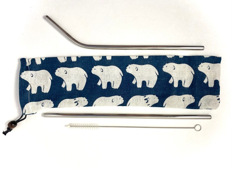 Pode incluir: Um conjunto de duas palhas reutiliz&aacute;veis de a&ccedil;o inoxid&aacute;vel com uma escova de limpeza e uma bolsa de tecido azul com um padr&atilde;o de ursos polares brancos.