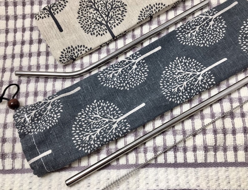 Pode incluir: Conjunto de tr&ecirc;s canudos de beber de a&ccedil;o inoxid&aacute;vel com uma escova de limpeza, em uma bolsa de tecido com padr&atilde;o cinza e branco.