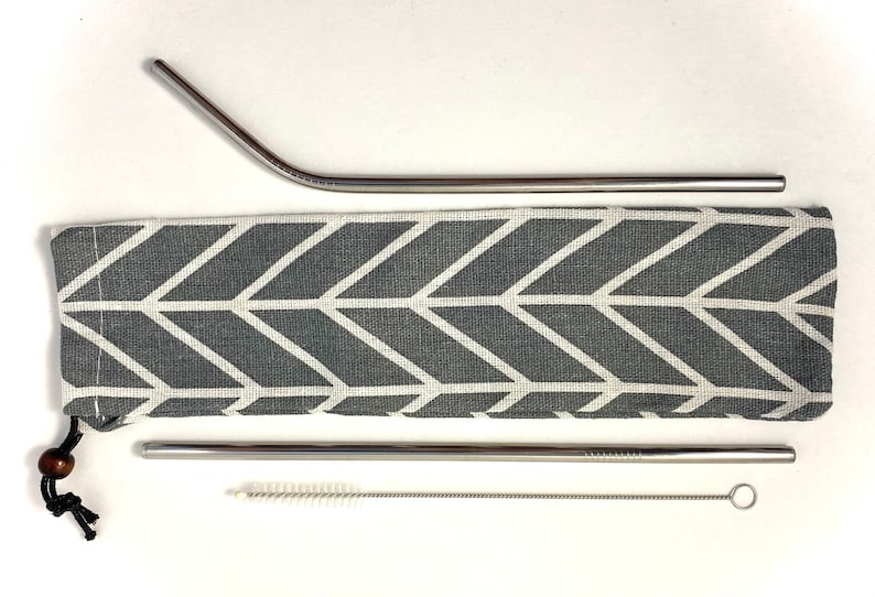 Pode incluir: Um conjunto de tr&ecirc;s canudos de beber de a&ccedil;o inoxid&aacute;vel com uma bolsa de transporte de tecido com padr&atilde;o cinza e branco e uma escova de limpeza.