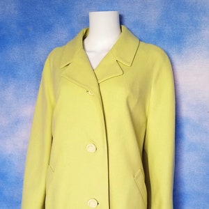 May include: A bright yellow coat with a classic collar and three white buttons. The coat is made of a smooth, lightweight fabric.
