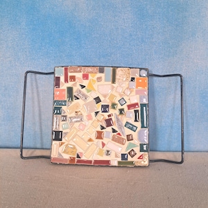 May include: A square mosaic tile tray with black metal handles. The tray is decorated with a variety of colorful tiles in shades of blue, green, red, yellow, and white.