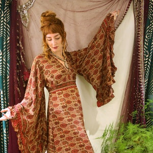 Long silk burgundy paisley patterned dress, with dramatic flared sleeves, tie waist fastening, slit at sides, inspired by Stevie Nicks, available in sizes Small Medium and large.