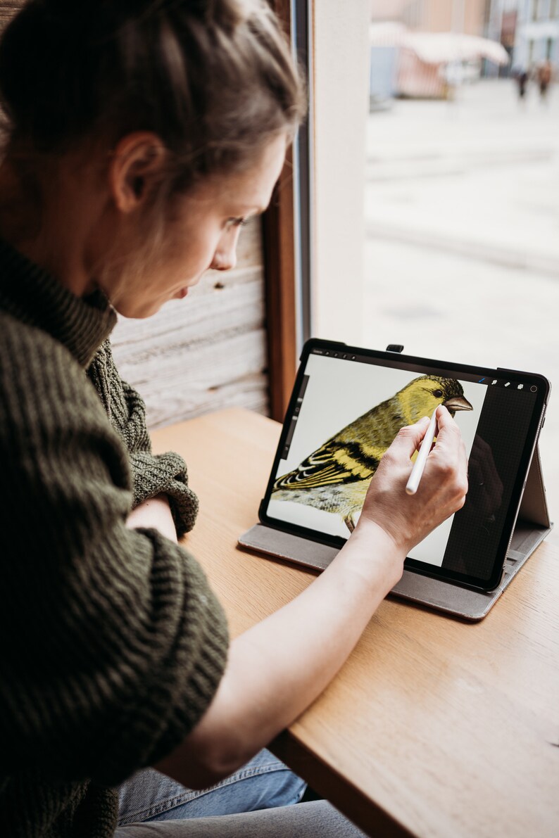 Puede incluir: Una persona usando un l&aacute;piz digital para dibujar un p&aacute;jaro amarillo en una tableta.