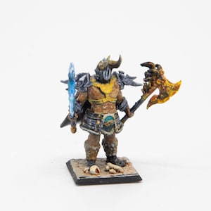 Op de afbeelding: Een geschilderd miniatuurfiguur van een krijger met een gehelmde helm, die een blauw zwaard en een grote bijl met een gele kling vasthoudt. De krijger draagt ​​een zwart harnas en een geel borststuk. Het figuur staat op een zwarte basis met een zandkleurig oppervlak.