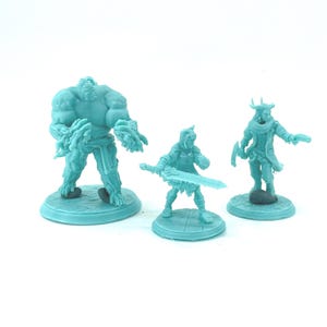 May include: Three teal-colored miniature fantasy figures. The figures include a large, muscular humanoid, a warrior with a sword, and a robed figure with a pistol. Each figure is on a circular base.