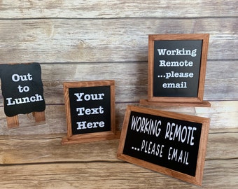 May include: A collection of small, wooden-framed chalkboard signs with white text. One sign reads "Out to Lunch," another says "Your Text Here," and two others display "Working Remote...please email."