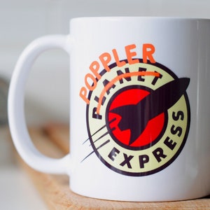 May include: White ceramic mug with a red, yellow, and black logo that says "Planet Express" with a rocket ship in the center. The word "Poppler" is written in orange above the logo.