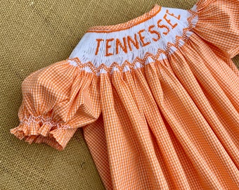 Puede incluir: Vestido de cuadros vichy naranja y blanco con un cuello bordado en blanco que dice "TENNESSEE".