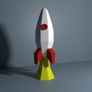 May include: A white and red paper rocket with a yellow base. The rocket has a red circle on the front.