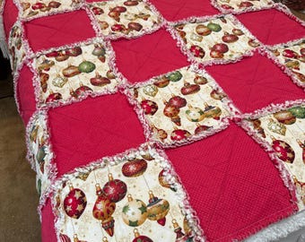 Könnte beinhalten: Eine rote und weiße Patchwork-Decke mit einem Weihnachtsbaumschmuckmuster. Die Decke besteht aus Stoffquadraten mit verschiedenen Mustern, darunter ein weißer Stoff mit goldenen und roten Ornamenten.