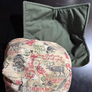 May include: Two quilted bowl cozies. One is olive green, the other is beige with a Christmas-themed print featuring reindeer, Christmas trees, and the words "Merry Christmas" in red and green.