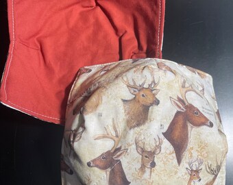 May include: A red quilted pot holder with a white trim and a beige fabric backing featuring a pattern of deer heads with Roman numerals and the text "American Game Birds".