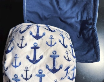 May include: Two quilted bowl cozies. One is white with a blue anchor pattern. The other is solid navy blue. Both are square shaped with white stitching. Nautical theme.