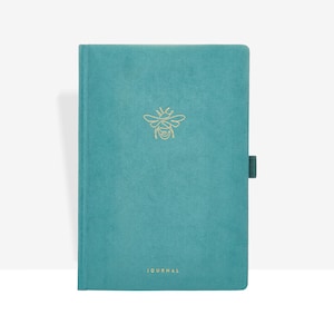 May include: Teal journal featuring a gold bee emblem and the word "JOURNAL". The journal has a teal elastic band closure. The cover has a textured appearance.