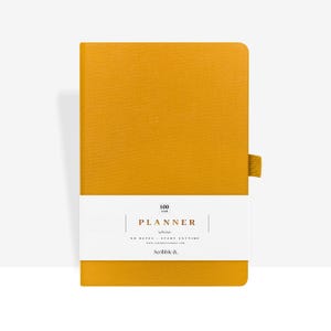 May include: Mustard-colored planner with a white band across the front. The band features the word "PLANNER" and the text "NO DATES - START ANYTIME". A mustard-colored ribbon bookmark is attached to the right side. The planner is 100 cm.
