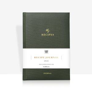 May include: A dark green recipe journal with gold lettering that reads "My Recipes" and "Recipe Journal". The journal has a white band with the text "120 GSM" and "Scribble &."