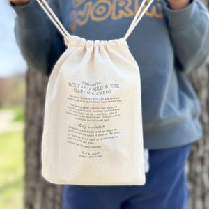 K&ouml;nnte beinhalten: Eine wei&szlig;e Kordeltasche mit einem Etikett, auf dem "Witencedor Jack Yard Bird & Egg Learning Cards" steht. Das Etikett beschreibt die Karten als eine lustige M&ouml;glichkeit f&uuml;r Kinder, spielerisch zu lernen. Die Tasche ist mit Karten gef&uuml;llt und hat einen Kordelverschluss.