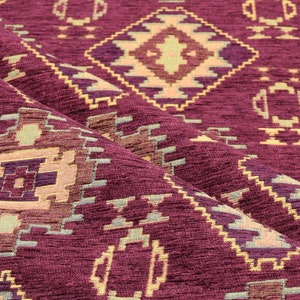Puede incluir: Primer plano de una tela color burdeos con un patr&oacute;n geom&eacute;trico en tonos beige, morado y verde. La tela tiene un aspecto texturizado y tejido.