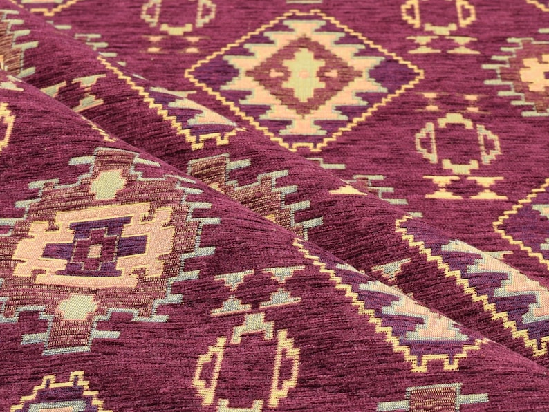 Puede incluir: Primer plano de una tela color burdeos con un patr&oacute;n geom&eacute;trico en tonos beige, morado y verde. La tela tiene un aspecto texturizado y tejido.