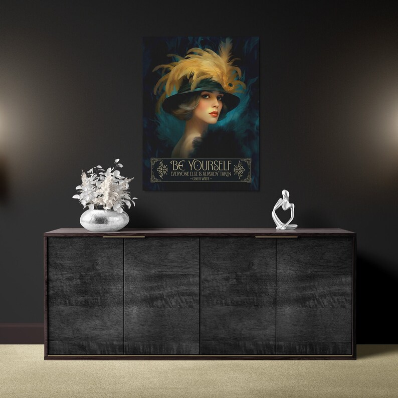 May include: A vintage-style poster with a woman wearing a black hat with feathers and a teal dress. The poster has a gold frame and the text "BE YOURSELF EVERYONE ELSE IS ALREADY TAKEN - OSCAR WILDE".