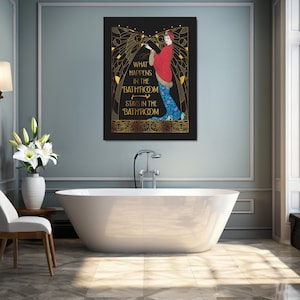 May include: A black and gold art print with a woman in a red and blue dress. The text on the print reads "What happens in the 'bathroom' stays in the 'bathroom'".