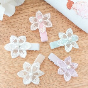 May include: Five flower hair clips with pearl centers. The clips are in shades of pink, white, light blue, and lavender.