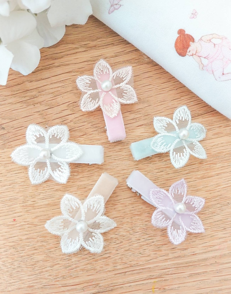 May include: Five flower hair clips with pearl centers. The clips are in shades of pink, white, light blue, and lavender.