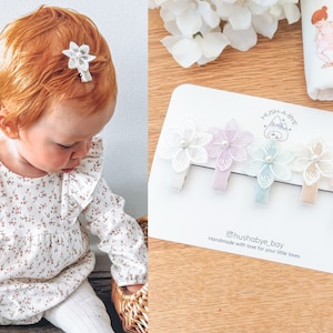 May include: Set of five pastel floral hair clips with pearl centers. The clips are on a white card with the text "Hush A Bye" and "@hushabye_boy Handmade with love for your little loves".