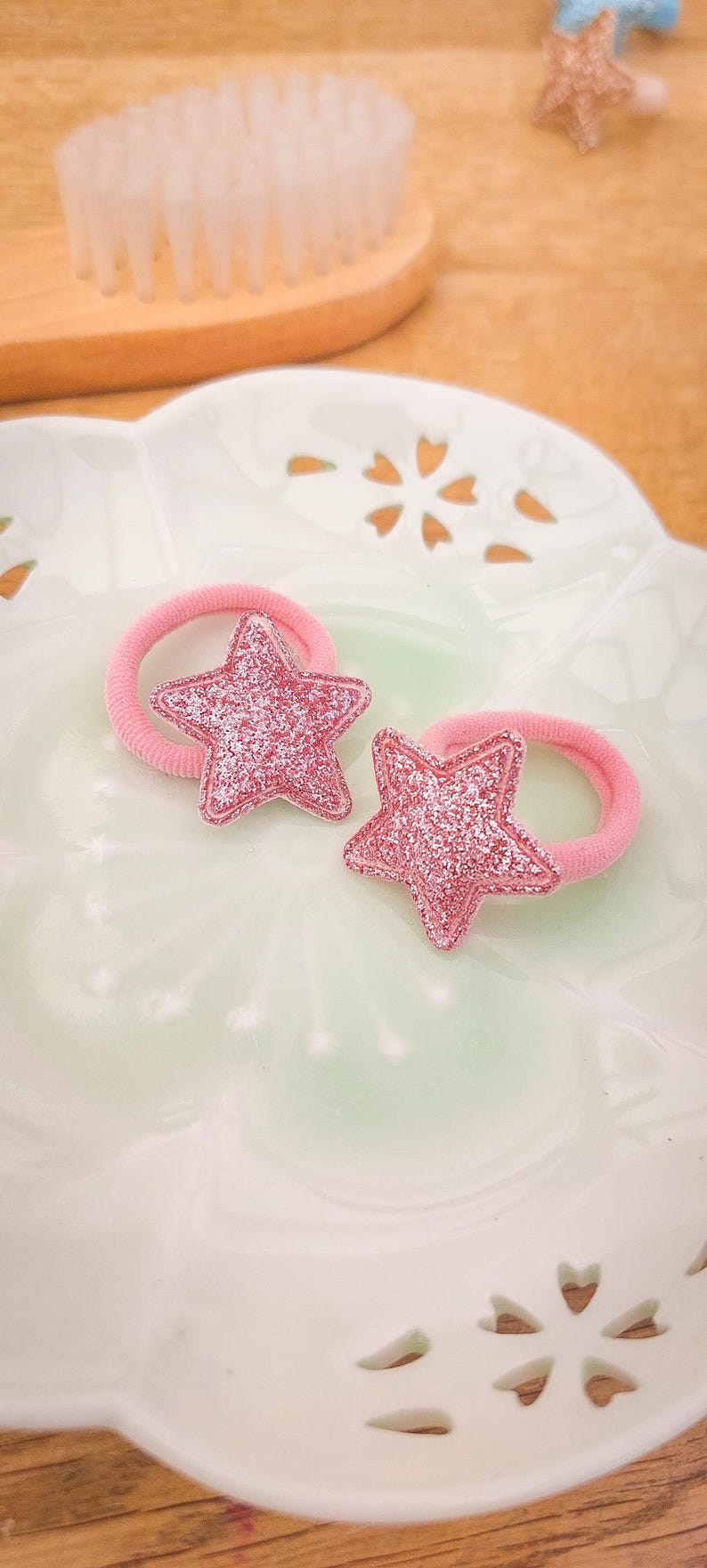 Pu&ograve; includere: Due elastici per capelli rosa con ciondoli a forma di stella rosa scintillante.