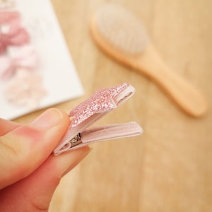 以下が含まれることがあります： ピンクのグリッタースターのヘアクリップで、ピンクのベルベットのバンドが付いています。