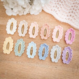 May include: A set of 12 crocheted hair clips in various pastel colors. Each clip features a delicate oval shape with a gold metal bar.