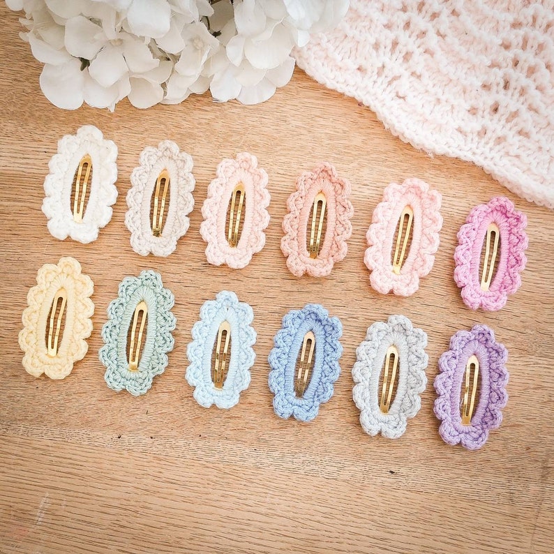 May include: A set of 12 crocheted hair clips in various pastel colors. Each clip features a delicate oval shape with a gold metal bar.