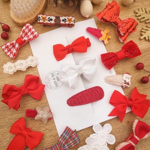 May include: A set of 12 Christmas-themed hair clips featuring red, white, and gold bows, stars, and lace. The clips are perfect for adding a festive touch to any outfit.